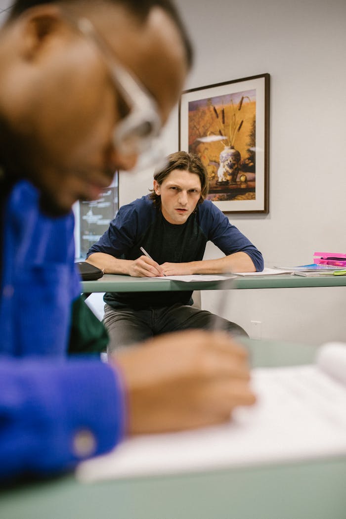 A student glancing at another student's paper, depicting cheating in a college classroom setting.
